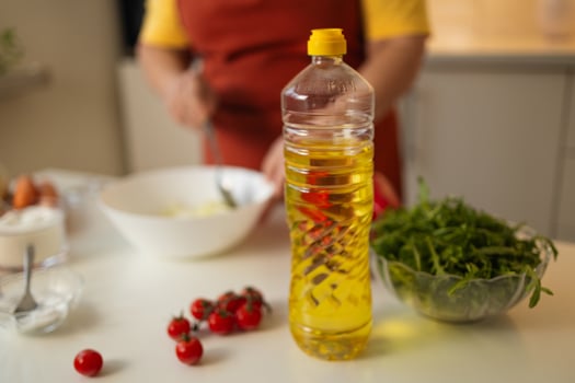 Cooking oil bottle in the kitchen with vegetables and fresh ingredients nearby photo