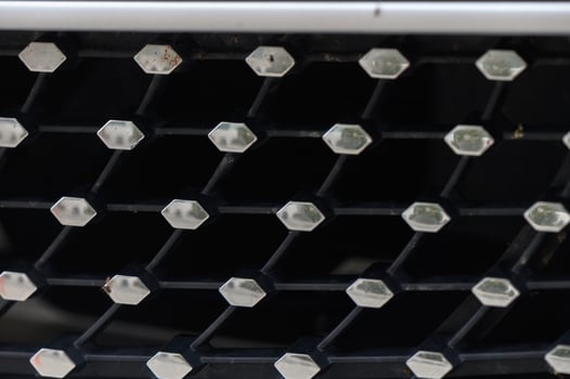Close-up view of an intricate car grille design showcasing geometric patterns and textures in a modern aesthetic photo