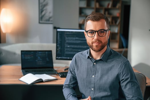 Software ,developer, is sitting and posing. Man in formal clothes is working in the modern office. Using computer photo