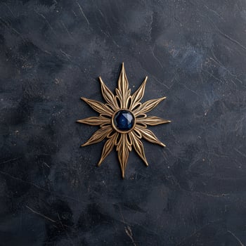 Golden sunburst brooch with a dark blue gemstone on a dark textured background photo