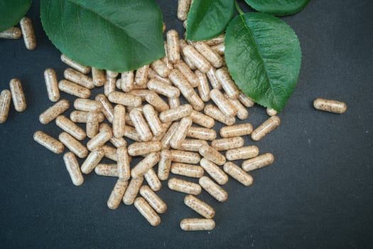 Capsules spills over green leaves on a dark surface photo