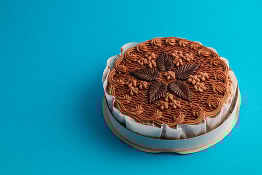 Delicious chocolate cake with intricate decoration on a vibrant blue background photo