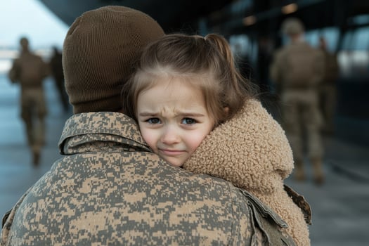 A little girl hugs a soldier, emotional goodbye photo