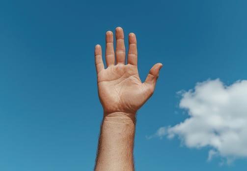 A hand reaching up to the blue sky photo