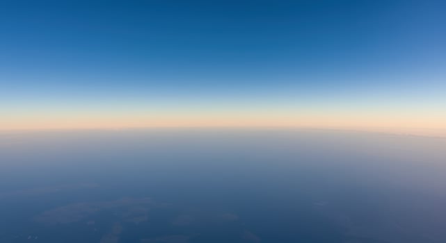 Aerial view of a serene horizon showcasing a gradient of blue sky meeting a foggy earth. photo