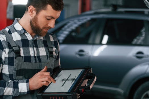 Graphic information is on the, tablet. Man in uniform is working in the auto salon photo