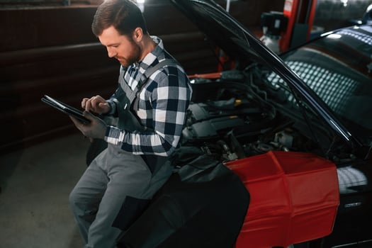 With tablet in hands. Man in uniform is working in the auto salon photo