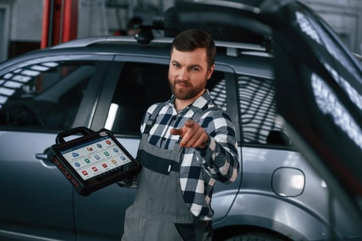 Showing gesture,and smiling. Holding tablet. Man in uniform is working in the auto salon photo