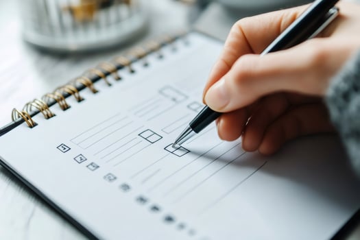 Woman checking boxes on checklist using pen in notebook photo
