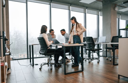 Against, big windows by the table. Four people are working in the office together photo