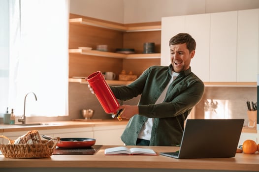 Holding a fire extinguisher, scared. Handsome man is on the kitchen at daytime photo