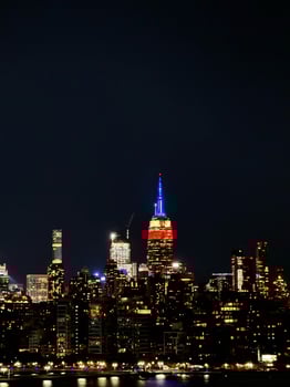 Empire State Building Shines Red Blue Gold Over New York Skyline at Night photo