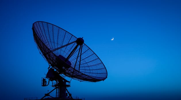 large satellite dish silhouetted against a twilight blue sky photo