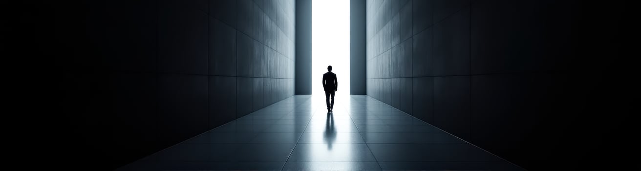 person in formal wear walks towards a bright light at the end of a dark corridor photo