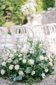 Large bouquet of flowers stands near white chairs in the park photo