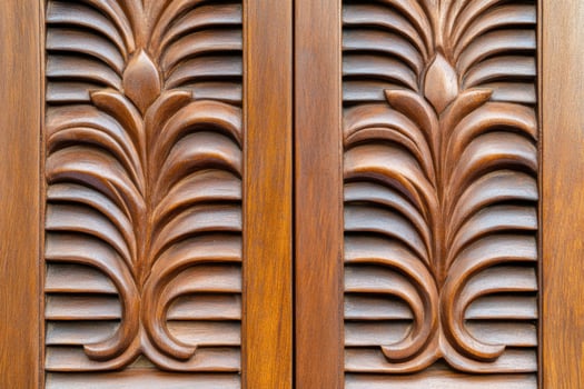 Intricate carved wooden doors and window shutters of a traditional Kerala home showcasing rich heritage and aged textures photo
