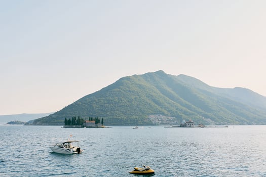 Motor boats are moored in the sea with St. George Island and the mountains in the background. Montenegro photo