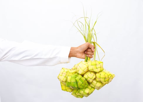 A Person's Hand Holding a Bunch of Ketupat, Traditional Ramadan Food photo