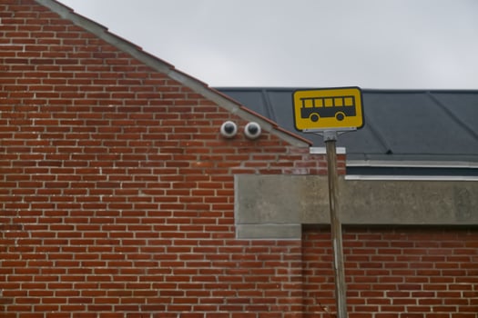 Bus Stop Sign in Front of Brick Building photo