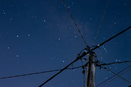 Electric pole with intersecting cables under a starry night sky. Long exposure photography with a clear night atmosphere. Concept of urban, technology, energy, and connectivity. Blur. photo