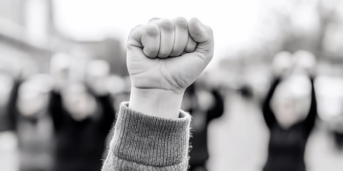 A black and white photo of a person holding up their fist