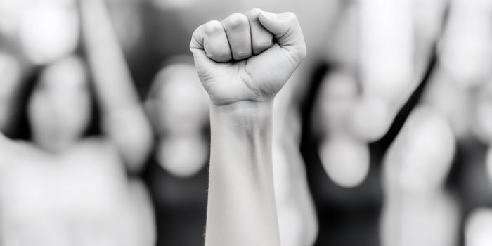 Woman's fist raised in the air with other people in the background photo