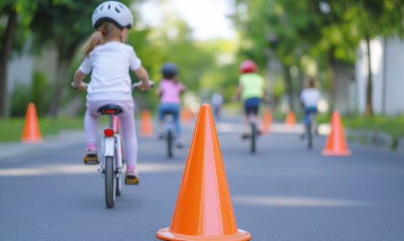 Children riding bikes in a road with orange cones photo