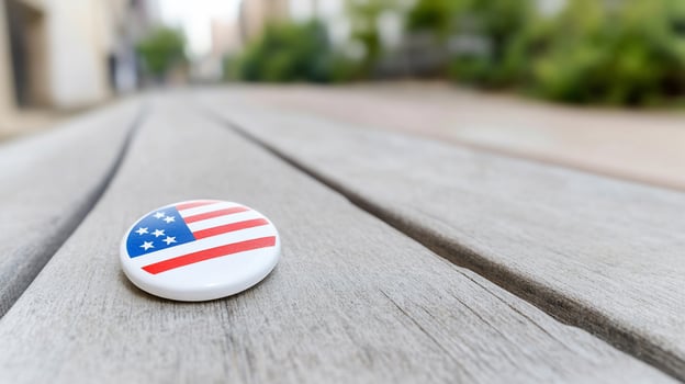 A button with the american flag on it sits on a wooden table photo