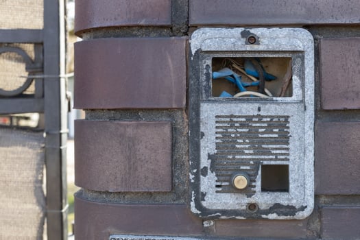 Old Damaged Intercom with Exposed Wires on Brick Wall photo