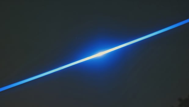 A blue light streaks in the dark night sky photo