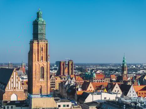 Aerial view of Wroclaw, Poland, highlighting St. Elizabeth's Church with its tall brick tower, surrounded by colorful historic buildings and red tiled roofs. photo