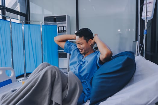 Asian man in hospital bed with his head on pillow photo