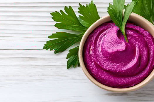 Beetroot hummus decorated with parsley leaves on white wooden table photo