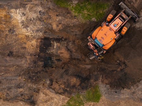 Aerial View of Construction Vehicle on Excavated Soil with Grass Patches photo