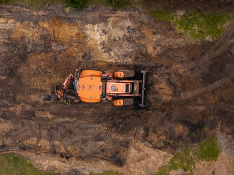 Overhead View of Orange Excavator at Construction Site with Soil photo