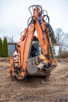 Orange Excavator on Construction Site with White Building in Background photo