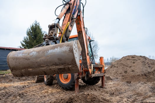 Orange Excavator at Construction Site with Dirt Piles and Tire Tracks photo