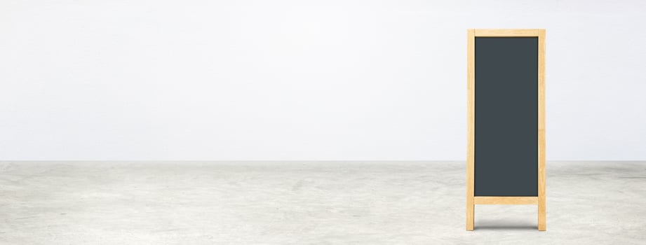 Blank blackboard on a concrete floor with a white wall. photo