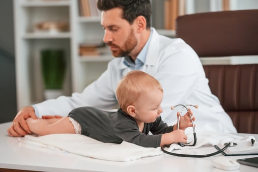 With stethoscope.. Doctor with little baby is working in the cabinet photo