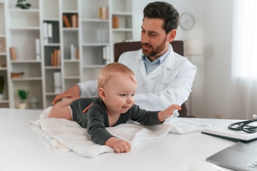 Toddler, is, lying down on the table. Doctor with little baby is working in the cabinet photo