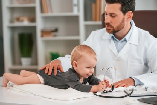 With stethoscope. Doctor with little baby is working in the cabinet photo