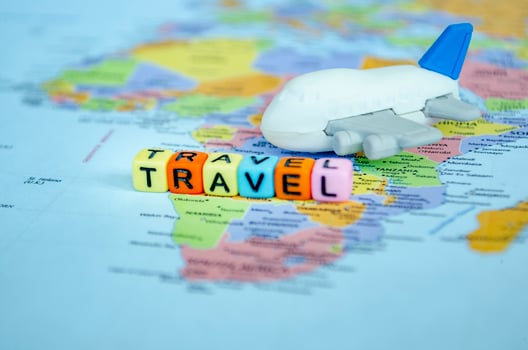 Travel text on plastic cubes with toy airplane placed on world map. Travel and destination concept photo