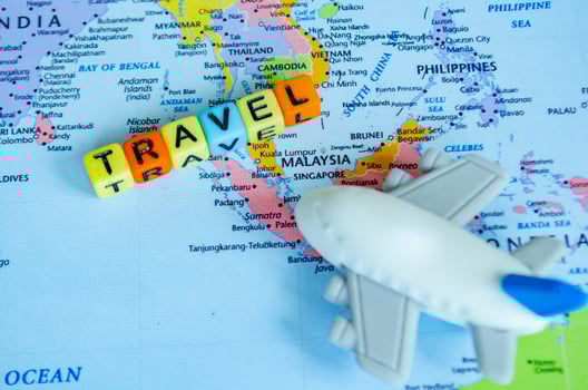 Top view of small toy airplane placed on a world map and plastic cubes with text TRAVEL. Travel and destination concept photo