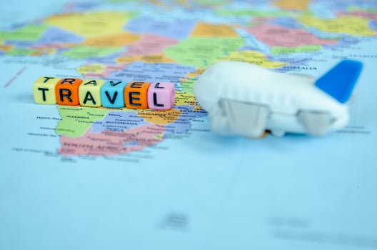 Small plastic cubes with text TRAVEL placed on world map with small airplane. Travel and exploration concept photo