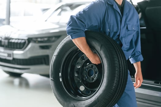 Tire replacement concept.. Man in blue uniform is working in the car service photo