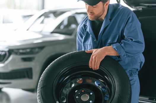Tire replacement, concept. Man in blue uniform is working in the car service photo