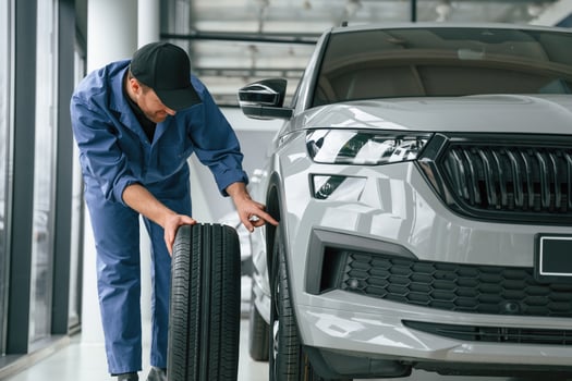 Changing the ,tire.. Man in blue uniform, is working in the car service photo