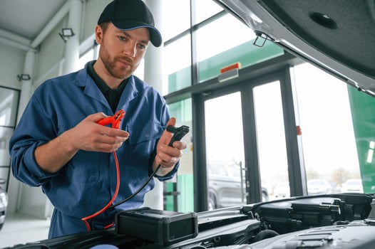 Testing, breakage by using electrical ,terminals. Man in blue uniform is working in the car service photo