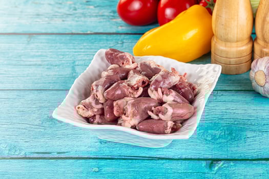 A bowl of raw meat sitting on a table next to a bunch of vegetables photo