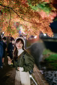 Asian woman in a fashionable jacket enjoys the beauty of urban nightfall in Japan. A festive portrait capturing Christmas cheer and snowy delight. photo